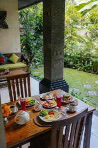 a wooden table with plates of food on it at Ubud Harmony Private Villa and Pool in Ubud