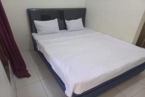 een bed met witte lakens en kussens in een kamer bij SPOT ON 93606 Juan Kostel 3 in Purwokerto