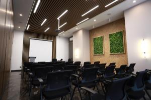 uma sala de conferências com cadeiras pretas e uma parede verde em IsraHotel Dushanbe em Dushanbe