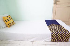 uma cama branca com duas almofadas em cima em SPOT ON 93611 Kost Pak Suyatno Syariah 2 em Ponorogo
