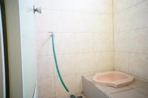 uma casa de banho com um chuveiro e um WC cor-de-rosa. em SPOT ON 93611 Kost Pak Suyatno Syariah 2 em Ponorogo