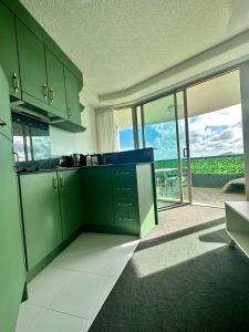 cocina con armarios verdes y vistas al océano en 8th Floor Sunny Escape at Landmark Resort en Mooloolaba