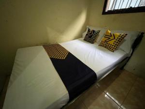 a bed with pillows on it in a room at SPOT ON 93621 Kost Bu Tutik Syariah in Lawang