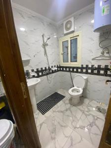 La salle de bains blanche est pourvue de toilettes et d'un lavabo. dans l'établissement شقة مودرن للايجار اليومي والاسبوعي, à Mansoura