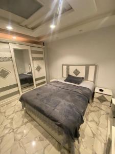 ein Schlafzimmer mit einem großen Bett und einem Spiegel in der Unterkunft شقة مودرن للايجار اليومي والاسبوعي in Mansoura