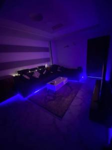 - un salon avec un éclairage violet et un canapé dans l'établissement شقة مودرن للايجار اليومي والاسبوعي, à Mansoura