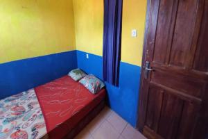ein kleines Bett in einem Zimmer mit einer Tür in der Unterkunft SPOT ON 93622 Wisma Dua Putra Syariah in Majalengka