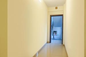 a hallway with a white wall and a door at FabHotel The Guest House in Pune