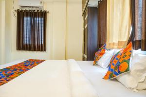 a bedroom with a large white bed with colorful pillows at FabHotel The Guest House in Pune