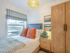 a bedroom with a bed with orange pillows and a window at Big Skies in Lowestoft