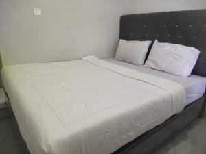 1 cama grande con sábanas y almohadas blancas en OYO 93630 Wongso Residence Syariah en Pangkalpinang
