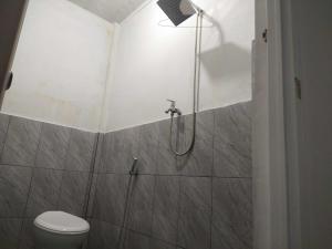 La salle de bains est pourvue d'une douche, de toilettes et d'une lumière. dans l'établissement OYO 93630 Wongso Residence Syariah, à Pangkal Pinang