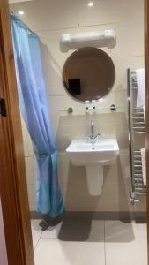 a bathroom with a sink and a blue shower curtain at Church Farm Accommodation in Bickenhill