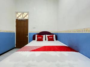 a bedroom with a bed with two red pillows on it at OYO 93629 Villa Cemara Syariah in Mojokerto