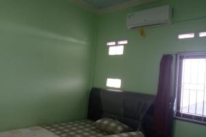 a green room with a bed and a window at OYO 93635 Rumah Singgah Cemara Syariah in Pekanbaru