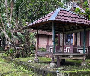 een klein huis met een bankje ervoor bij OYO 93638 Lotus Guest House in Lombok