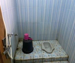 a small bathroom with a toilet with a pink hat on it at SPOT ON 93639 Kaila Guesthouse in Labuan Lombok