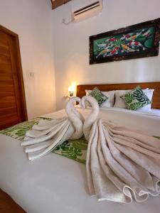 two towel swans sitting on top of a bed at Wahyu Masari Homestay in Nusa Penida