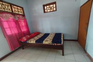 una piccola camera da letto con un letto e due finestre di Hotel O Dannis Homestay Near Musholla Al Istiqomah Terawangan a Lombok