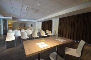 Turin Airport Hotel & Residence في سان فرانشيسكو أل كامبو: قاعة اجتماعات مع طاولة طويلة وكراسي بيضاء
