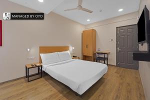 a bedroom with a white bed and a flat screen tv at Super Townhouse OMR Laxmi Nagar in Chennai