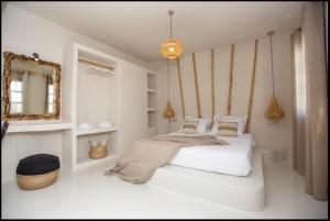 a white bedroom with a bed and a mirror at Ampelos Prokopios in Agios Prokopios