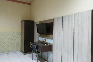 a room with a desk with a tv and a chair at OYO 93652 Karunia Kost & Penginapan 