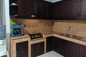 a kitchen with dark brown cabinets and a sink at OYO 93652 Karunia Kost & Penginapan 