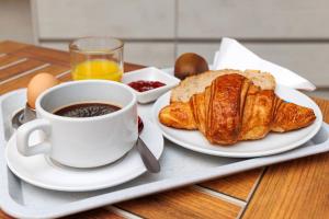 bandeja de desayuno con una taza de café y cruasanes en Logis Hôtel Le Rochelois, en La Rochelle