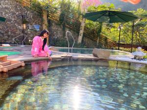 和平的住宿－統一渡假村- 台中谷關溫泉養生會館，坐在游泳池旁的身着粉红色衣服的女人
