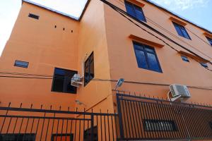 un edificio naranja con ventanas y una valla en OYO 93664 Homestay Purirano en Lepoleop