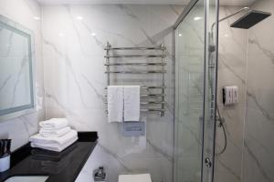 a bathroom with a shower and a sink and towels at Arman Dala Resort in Kaskelen