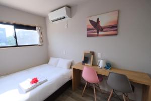 宫古岛最高の夏にするための特別割引 海外のようなロケーションのコンテナ型ホテル的一间卧室配有一张床和一张桌子,墙上设有冲浪板