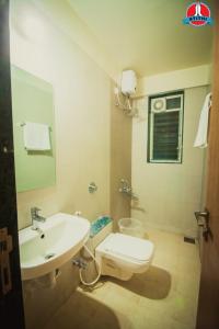 a bathroom with a white toilet and a sink at Atithi Service Apartment in Pune