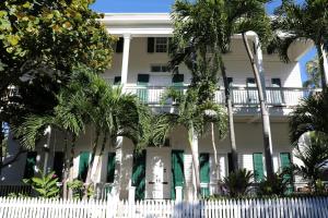 a white fence in front of a white house with palm trees at Ridley House - Key West Historic Inns in Key West