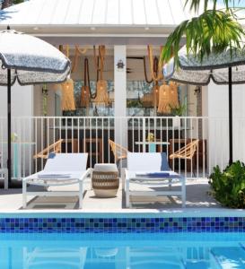 Duas cadeiras e guarda-sóis ao lado de uma piscina em Ridley House - Key West Historic Inns em Key West