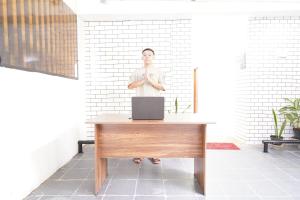 Ein Mann steht hinter einem Schreibtisch mit einem Laptop. in der Unterkunft SPOT ON 93624 Damai 3 Guest House Syariah in Bandung
