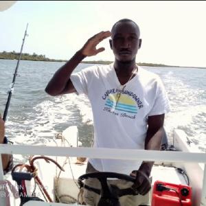 assoukatene lodge في كاب سكيرينج: رجل يقف على قارب في الماء
