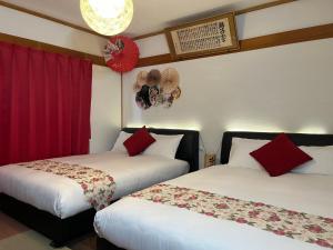 2 bedden in een hotelkamer met rode gordijnen bij Yokkaichi City Guest House in Yokkaichi