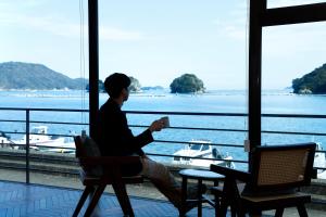 a man sitting in a chair looking out at the water at お宿行灯鳥羽 in Toba