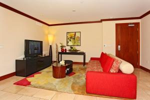 a living room with a red couch and a television at Ko Olina Beach Villas B204 in Kapolei