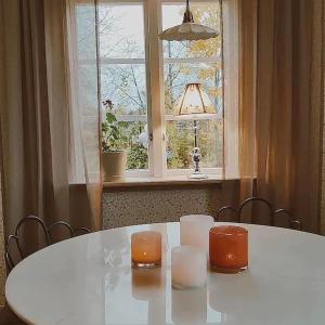 une table blanche avec deux bougies et une fenêtre dans l'établissement Villa Åmmeberg, à Åmmeberg