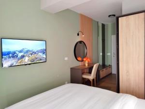 Schlafzimmer mit einem Bett und einem Schreibtisch mit einem TV an der Wand in der Unterkunft Urban Vista Apartments in Ohrid