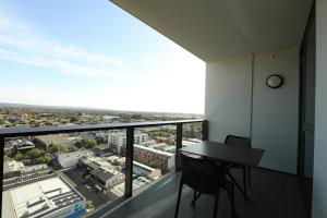 a balcony with a table and chairs and a view at CBD Stunning TOP Floor View - FREE Parking FREE Netflix FREE Gym FREE Pool FREE Sauna FREE BBQ Area FREE Coffee in Adelaide