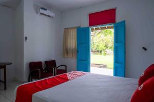 OYO 93604 Hepi Bungalow Lovina في Panji: غرفة نوم بسرير بأبواب وكراسي زرقاء