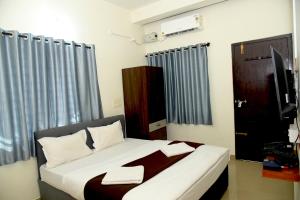 a bedroom with a bed and a television in it at Hotel Aradhya Inn Deralakatte in Mangalore
