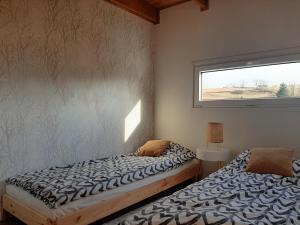 two beds in a room with a window at Antracytowe Domki w Górach Sowich in Sierpnica