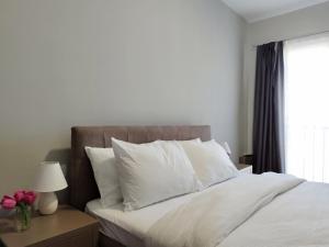 ein Schlafzimmer mit einem Bett mit weißen Kissen und einem Fenster in der Unterkunft Urban Vista Apartments in Ohrid