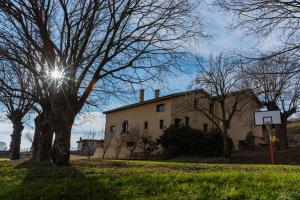 Un edificio con il sole che splende dietro un albero di Casa Vella del Cuní a Roda del Ter