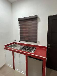 uma cozinha com um fogão vermelho e um lavatório em Departamento Diegos cabo em Cabo San Lucas